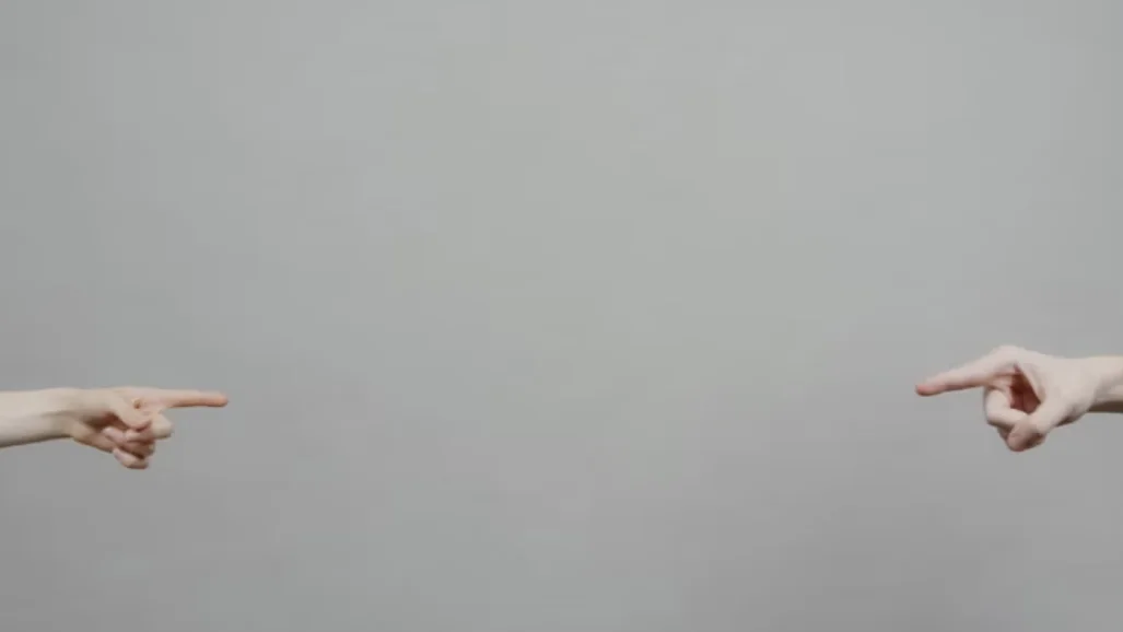 How to choose a coach: two hands pointing towards each other across an empty grey space