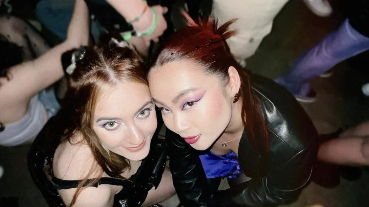 Mickey Jones, red hair and purple eyeliner, photographed from above with a friend at a party