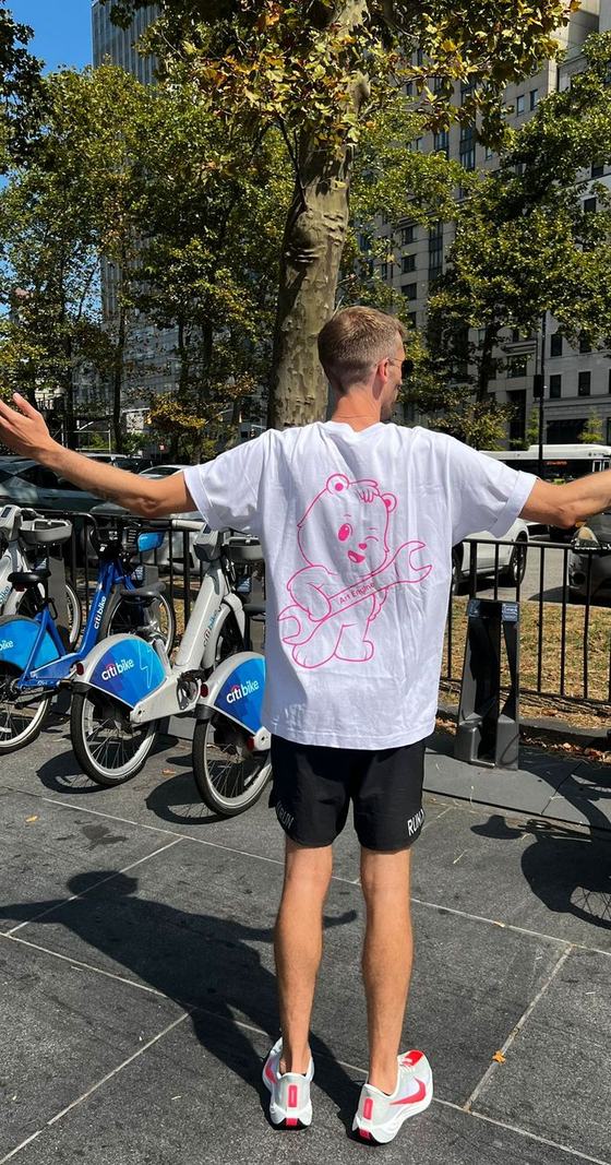 Someone in New York with arms spread wide, the winking bear across the back of their tee shirt