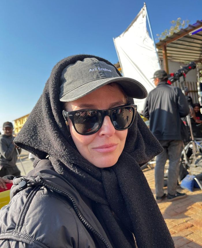 A woman in sunglasses and an Art Engine cap on a film set in the sun