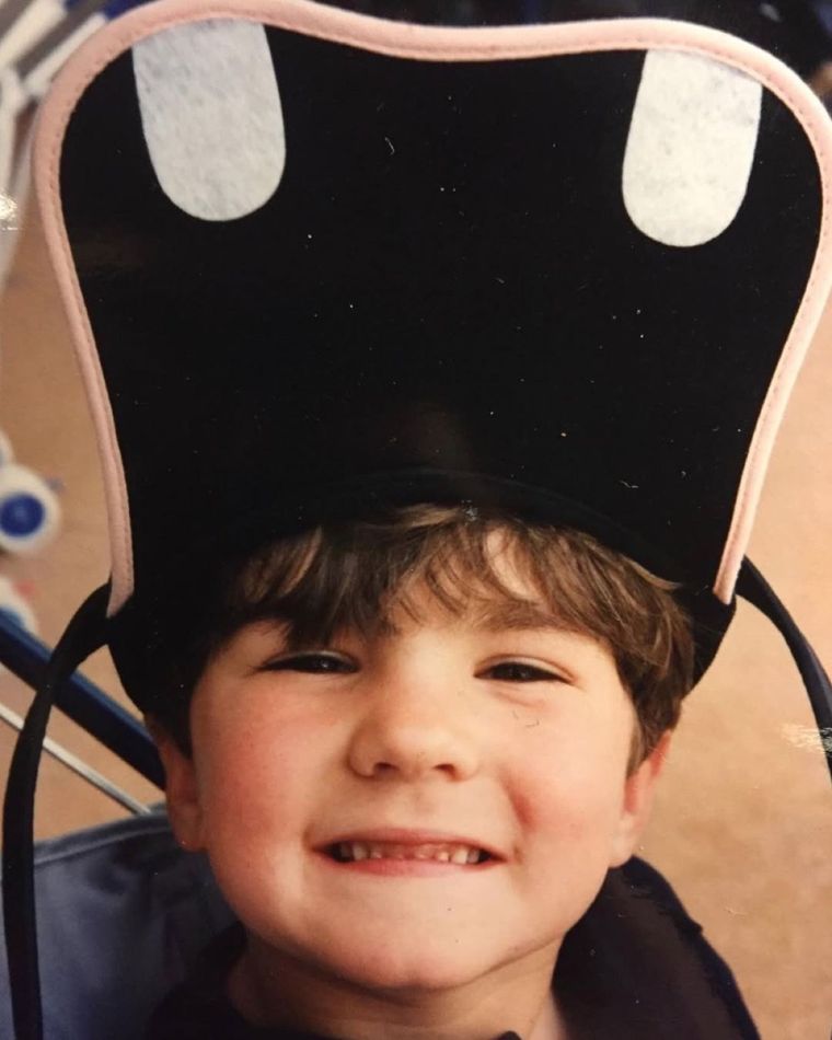 James as a young boy, grinning in an oversized hat