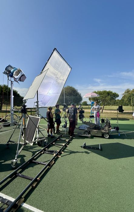 A film set in the sun, lighting rig up and crew working